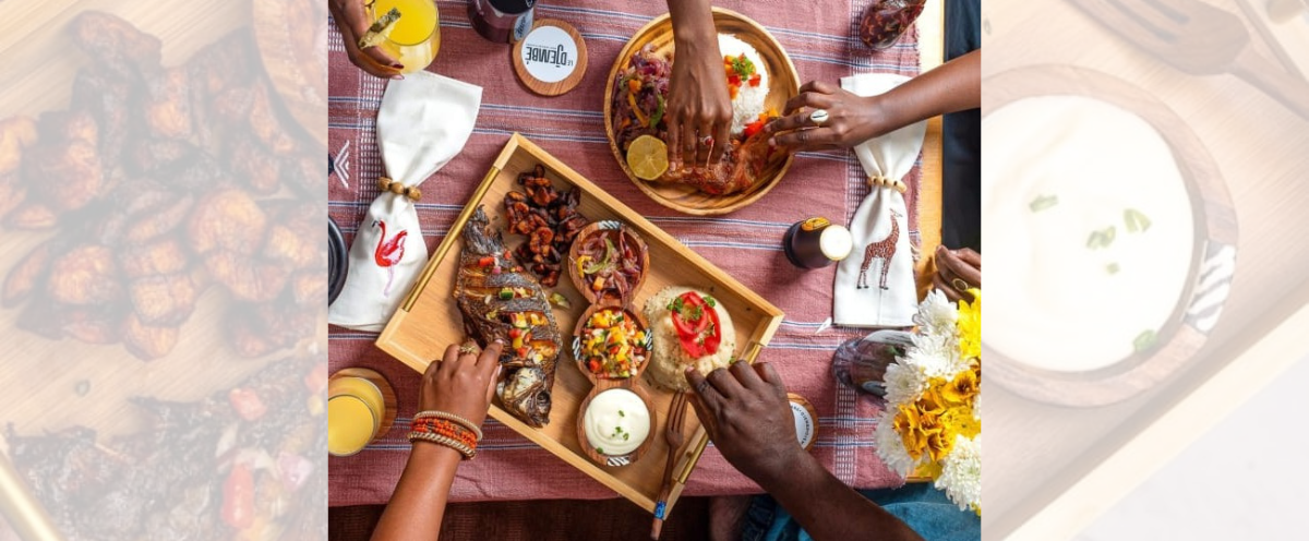 People enjoying a meal together with a focus on a wooden tray of food.