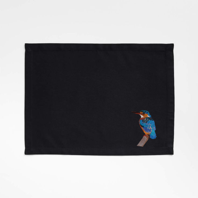 Black tablemat with embroidered bird  on a white background