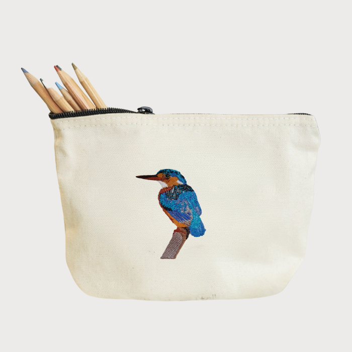 Beige pouch with bird Embroidery and pencils on a white background