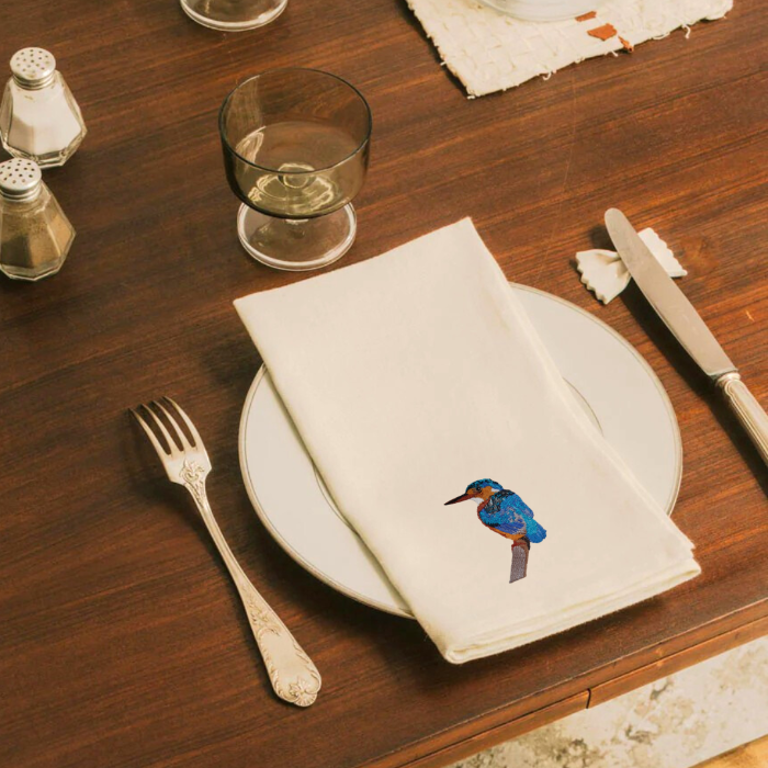 Napkin with a bird embroidery on a wooden table setting