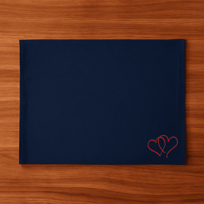 Navy blue placemat with red heart embroidery on a wooden surface