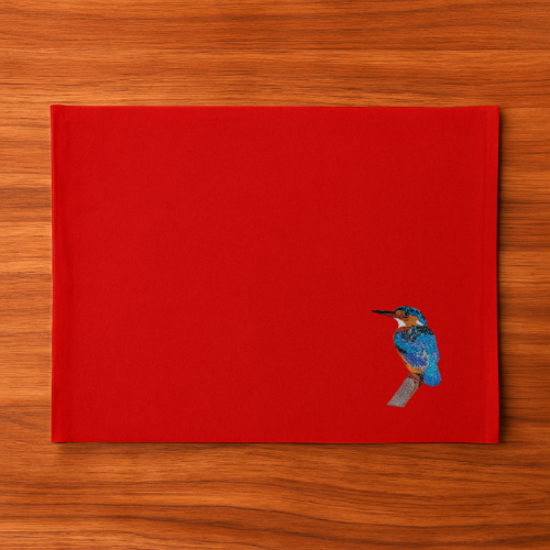 Red Tablemat with a  bird embroidery on a wooden surface