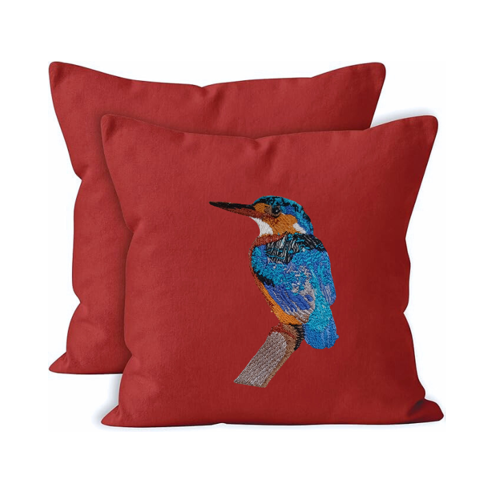 Red pillow with embroidered bird design on a white background