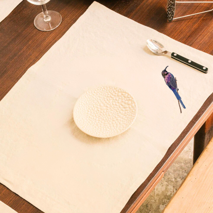 Beige dining mat with embroidered bird on a dining setting