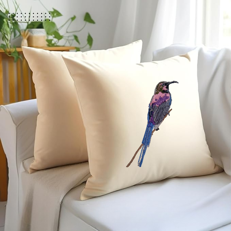 Beige pillow with a bird embroidery  on a white couch