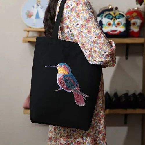 ILISAH Canvas Tote featuring a vibrant hummingbird design, available in black, burnt orange, and navy blue, perfect for ev...